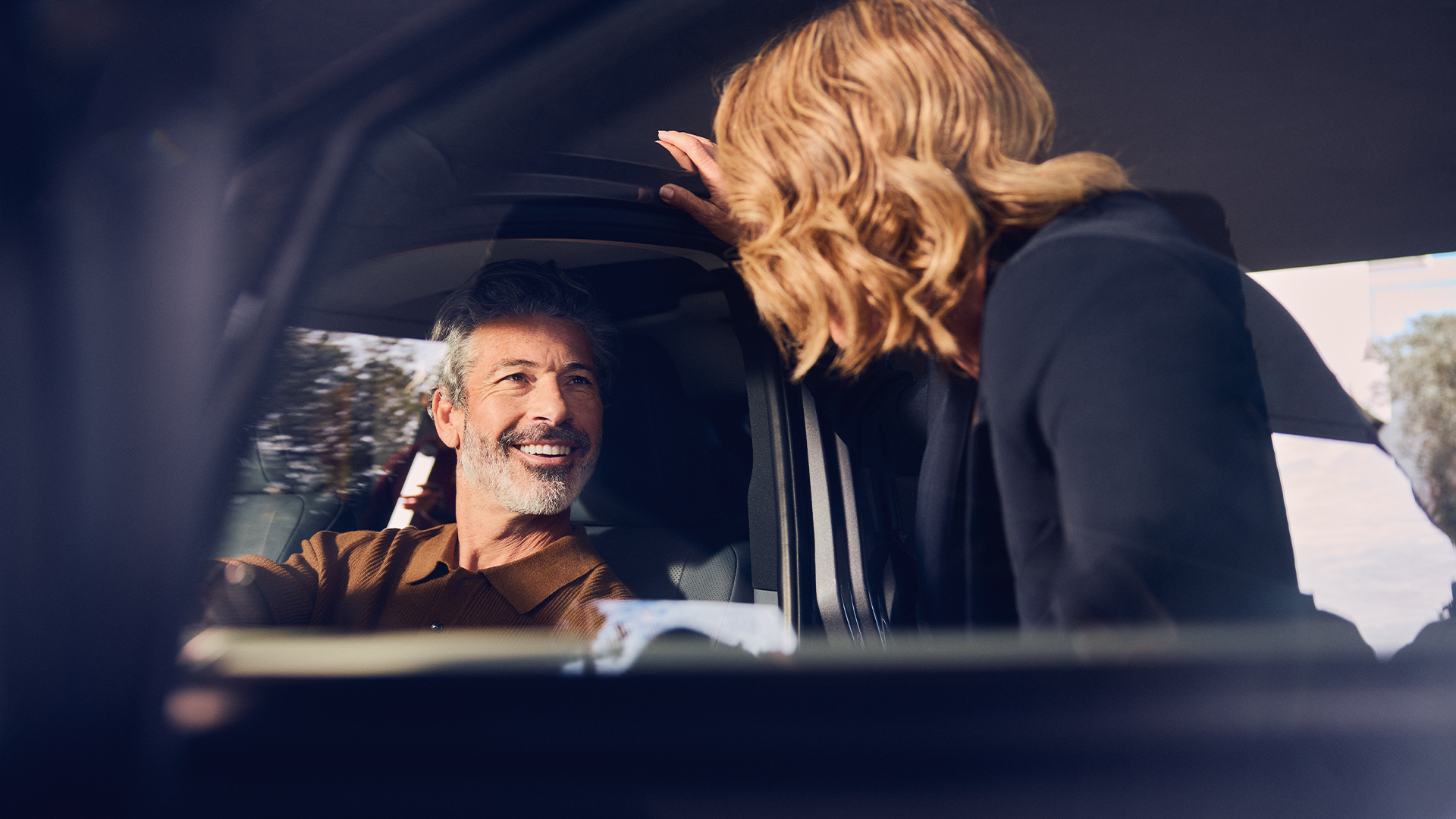 Un conductor sonriendo a una persona se paró en la puerta de un Lexus estacionado